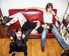 three young women laying on a red couch