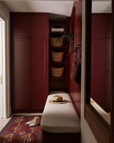 a room with red cabinets and a bench in the corner, next to a door