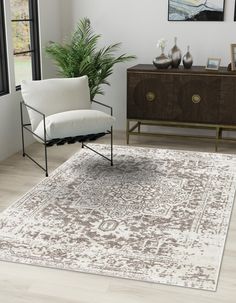 a living room area with a rug, chair and sideboard