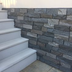 a stone wall next to some white stairs