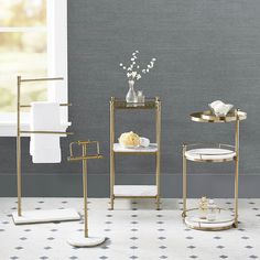 three gold - plated bathroom accessories are displayed in front of a gray wall and floor