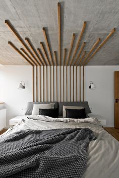 the bed is made up with black and white pillows, blankets, and wooden slats