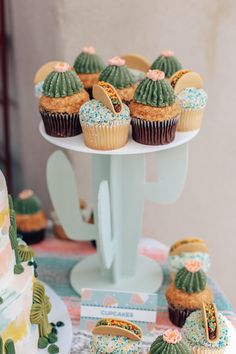 cupcakes are arranged on a cake stand with cactus decorations and desert themed frosting