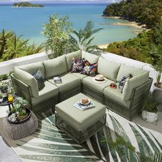 an outdoor living room with green furniture overlooking the ocean