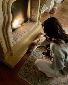 a woman kneeling down next to a fireplace