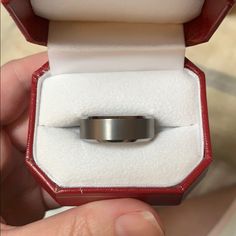 someone is holding their wedding ring in a red and white box with its lid open