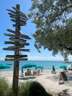 there are many signs on the beach pointing to different destinations and places that you can see