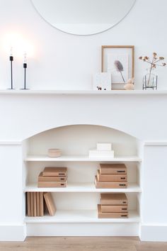 a white fireplace with books on it and a mirror above the fire place in front of it