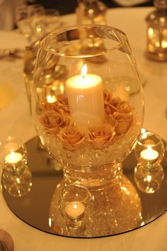 a candle is lit in a glass bowl on a table with candles and other decorations