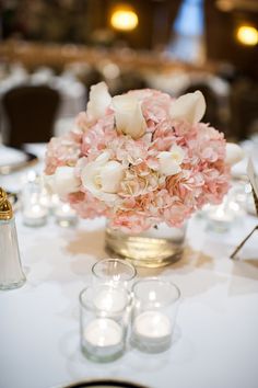 the centerpieces are arranged in glass vases with white and pink flowers on them