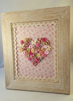 a heart made out of buttons in a frame