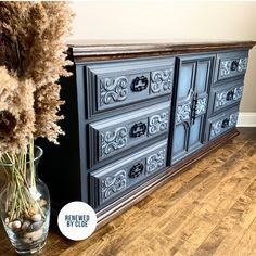 an old dresser has been painted blue and is next to a vase with dry grass in it