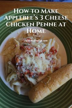 a green plate topped with pasta and meat next to a roll on top of a table