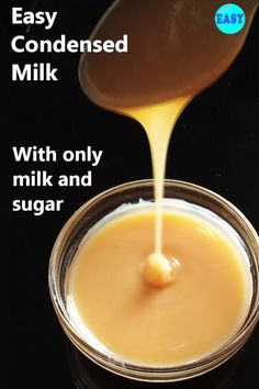 a spoon pouring liquid into a glass bowl filled with milk and orange juice, on top of a black surface