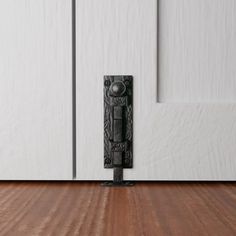 an ornate door handle on a white wooden door with wood flooring and paneling