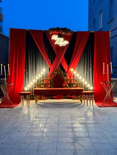 a stage set up with red drapes and lights on the sides, surrounded by candles