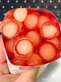 a hand holding a plastic container filled with fruit