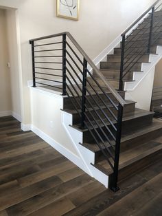 a stair case with metal handrails and wood flooring in an empty room