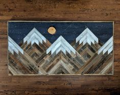 a wood panel with mountains painted on it and a moon in the sky above them