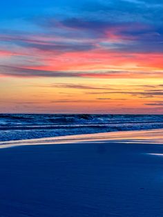 the sun is setting at the beach with waves coming in