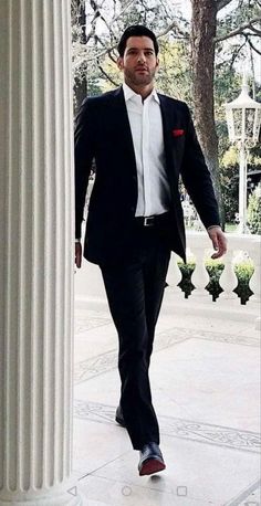 a man in a tuxedo walking down the street with his hand in his pocket