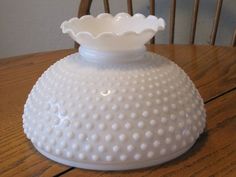 a white vase sitting on top of a wooden table