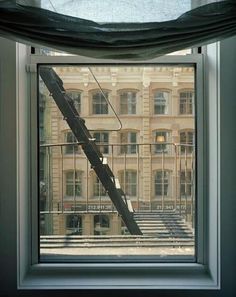 an open window with a view of a building and stairs in front of the window