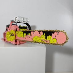 a pink snowboard with yellow and black designs on it sitting on a white pedestal