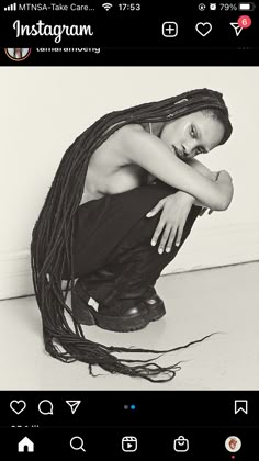 a black and white photo of a woman with dreadlocks on her head sitting down