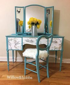 a blue vanity with flowers on it and a mirror in the corner next to it