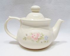 a white tea pot with flowers painted on it