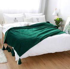 a bed with white sheets and green blankets