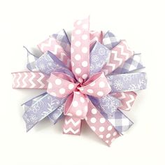 a pink and purple bow with white polka dots on the top, sitting on a white surface