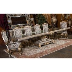 an ornate dining room table and chairs with mirrors on the wall behind them, along with a rug in front of it