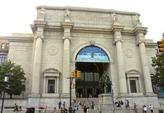 people are walking around in front of a large building with columns and arches on it