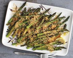 asparagus with parmesan cheese and lemon wedges on a white plate