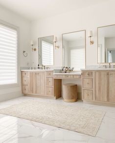 a bathroom with two sinks, mirrors and a rug on the floor in front of it