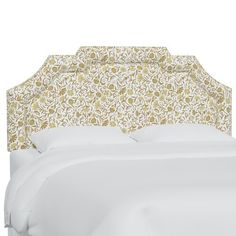 an upholstered headboard on a bed with white linens and floral designs