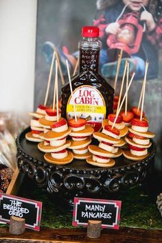 there are many mini sandwiches and ketchup bottles on the table with little sticks sticking out of them