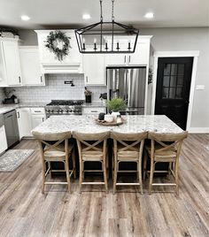 a kitchen with white cabinets and an island in the middle, surrounded by wooden flooring