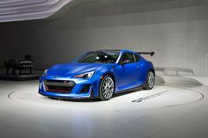 the blue sports car is on display at an auto show in front of a white wall