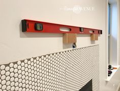 there is a red shelf on the wall next to a white and black tiled wall