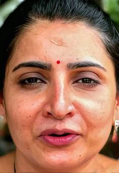 a close up of a person wearing a necklace and nose piercings on her forehead