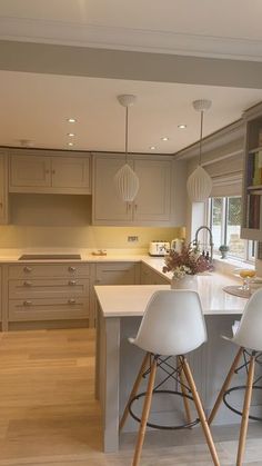 two white chairs sitting in front of a kitchen island with bookshelves on it