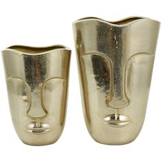 two gold vases sitting side by side on a white background, one is shaped like a face