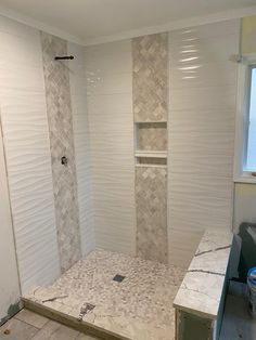 a bathroom that is being remodeled with tile on the floor and shower stall door open