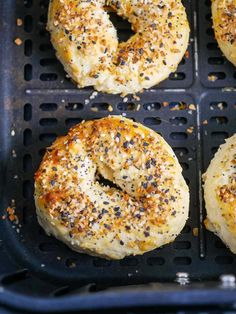 four bagels with poppy seed sprinkled on them in a black grill pan