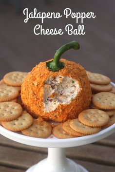 an appetizer with crackers and cheese is on a white cake plate that has the words jalapeno popper cheese ball on it