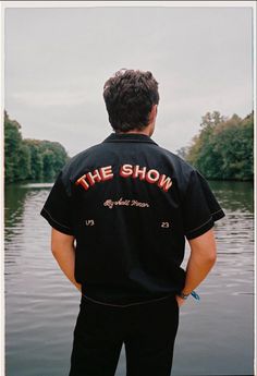 a man standing on the edge of a body of water with his back to the camera