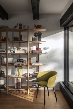 a yellow chair sitting in front of a book shelf